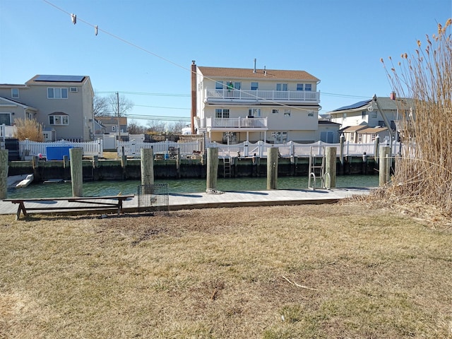 view of dock with a lawn, a water view, and a residential view