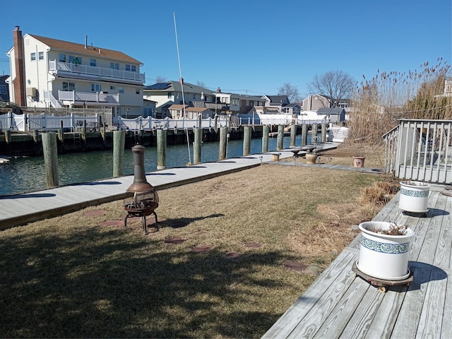 dock area featuring a yard, a residential view, a fire pit, and a water view