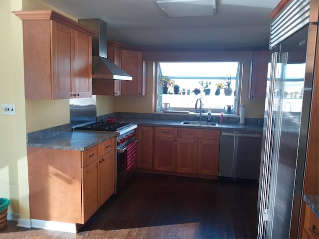 kitchen featuring a sink, high end appliances, dark wood finished floors, and wall chimney range hood