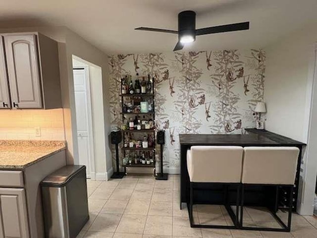 interior space featuring tasteful backsplash, light tile patterned flooring, a ceiling fan, and wallpapered walls