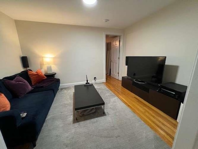 living area featuring baseboards and light wood finished floors