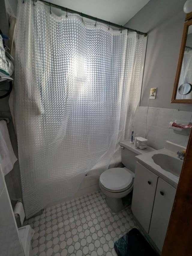 full bathroom with shower / bathtub combination with curtain, toilet, tile walls, and vanity