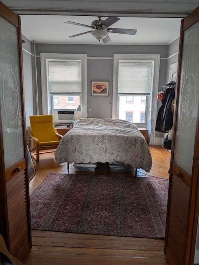 bedroom featuring a ceiling fan, multiple windows, and wood finished floors