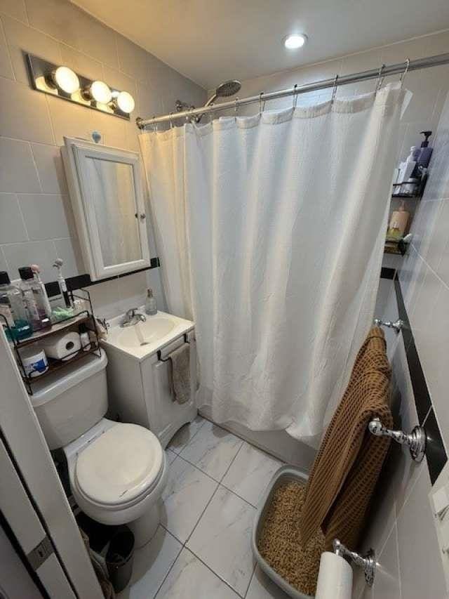 bathroom featuring marble finish floor, vanity, toilet, and shower / bath combo with shower curtain