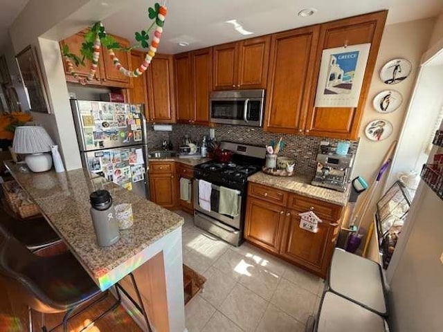 kitchen featuring brown cabinetry, stainless steel appliances, and light stone counters