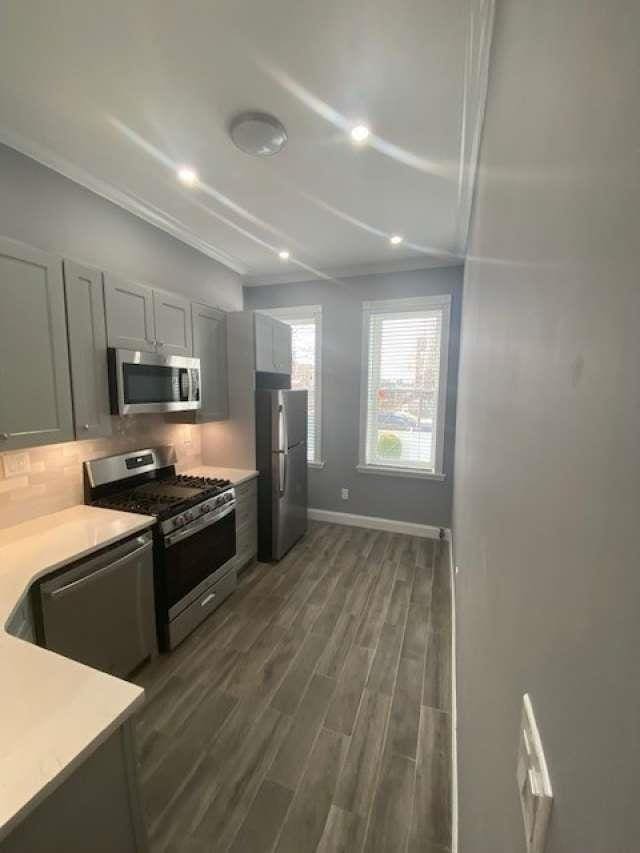 kitchen with baseboards, dark wood finished floors, stainless steel appliances, light countertops, and tasteful backsplash