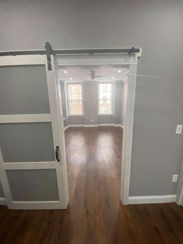 hallway featuring baseboards, a barn door, and wood finished floors