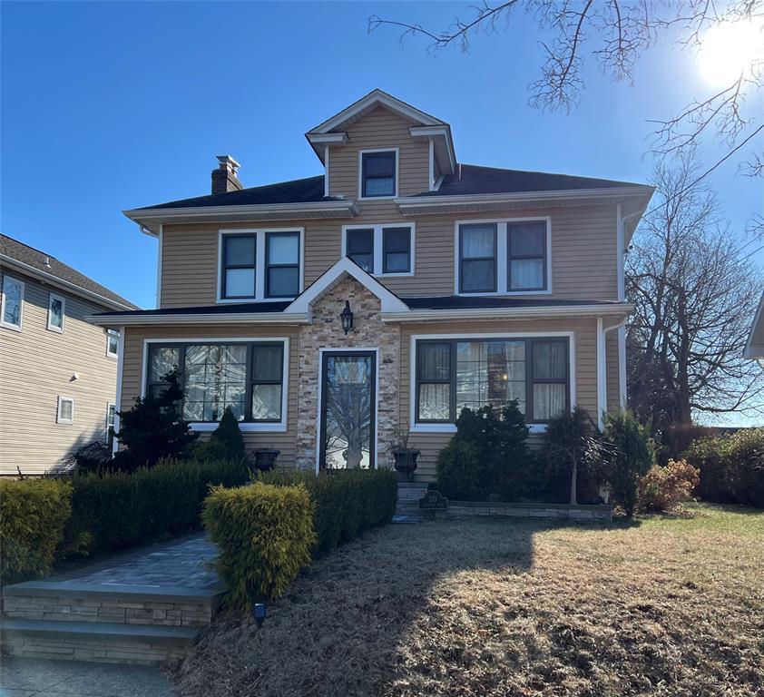 american foursquare style home featuring stone siding and a chimney