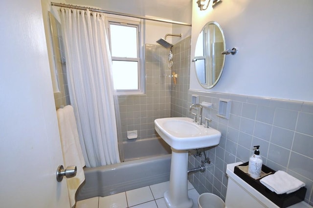 bathroom featuring tile patterned floors, a wainscoted wall, shower / bath combo, a sink, and tile walls