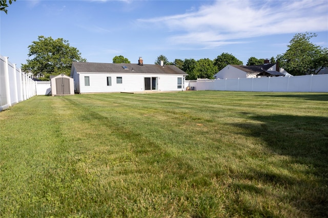 back of property with a yard, a storage shed, a fenced backyard, and an outdoor structure