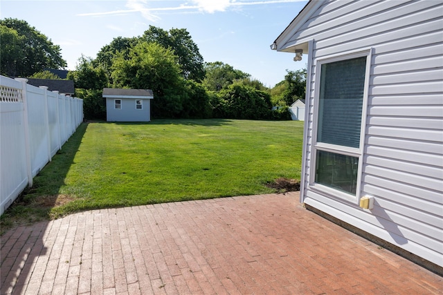 view of yard featuring a storage unit, a fenced backyard, an outdoor structure, and a patio area