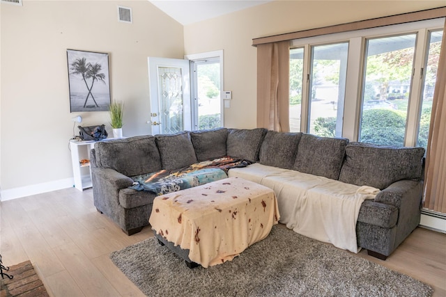 living room featuring visible vents, lofted ceiling, a healthy amount of sunlight, and light wood finished floors