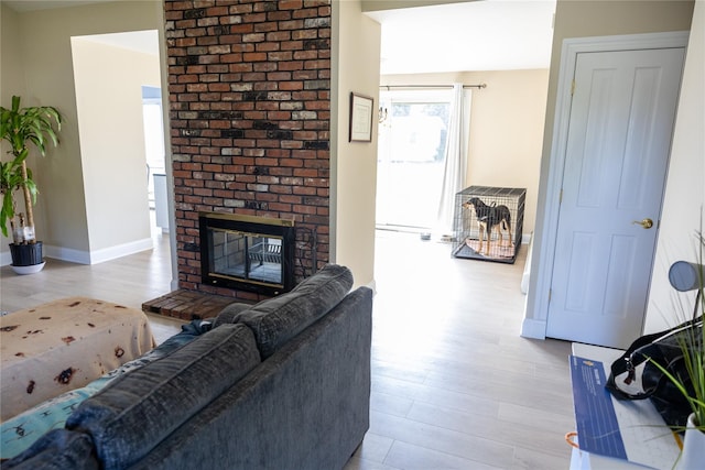 living room featuring a fireplace, baseboards, and wood finished floors