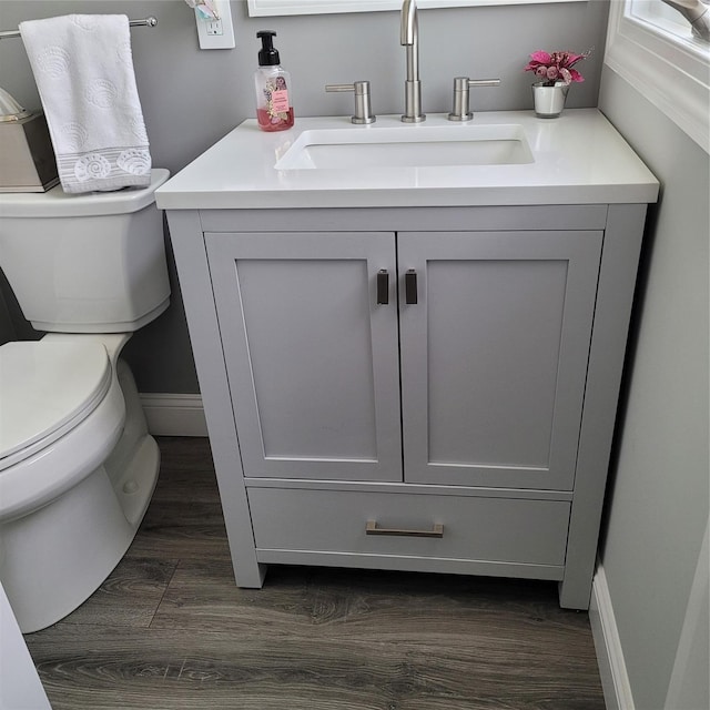 bathroom featuring vanity, toilet, wood finished floors, and baseboards