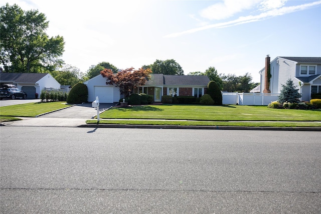 view of front of home with a garage, driveway, a front yard, and fence