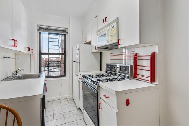 kitchen with white appliances, white cabinetry, light countertops, and a sink