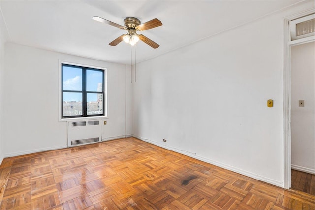 empty room with radiator heating unit, a ceiling fan, and baseboards