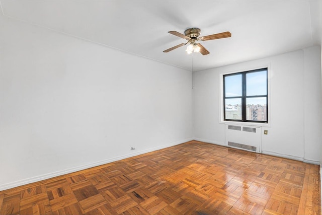 spare room featuring a ceiling fan, radiator heating unit, and baseboards