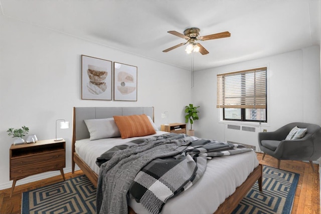 bedroom with radiator heating unit, a ceiling fan, and wood finished floors