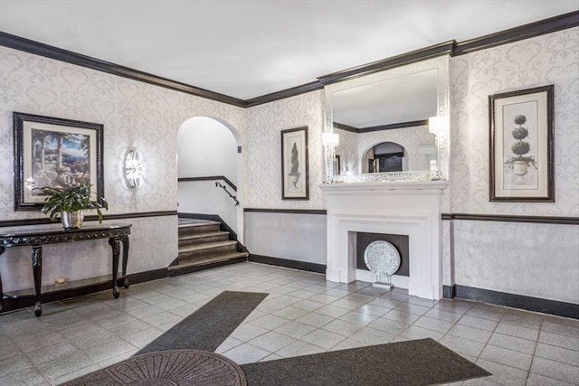 living area with wainscoting, wallpapered walls, baseboards, and ornamental molding