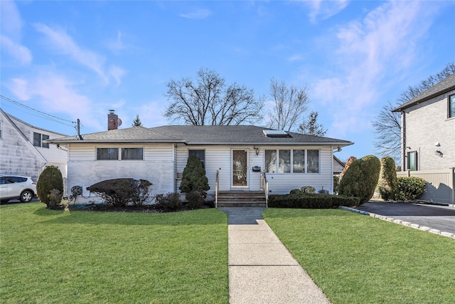 view of front of home featuring roof with shingles, a chimney, and a front lawn