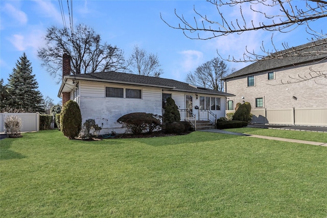 view of front of property featuring brick siding, a chimney, a front lawn, and fence