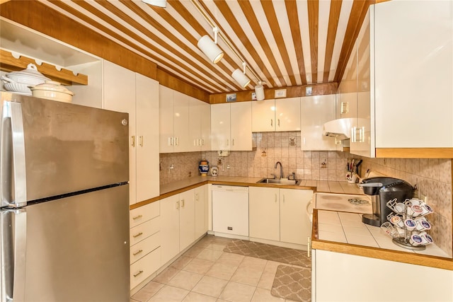 kitchen featuring decorative backsplash, white dishwasher, freestanding refrigerator, and a sink