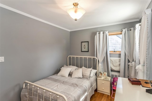 bedroom with wood finished floors and ornamental molding