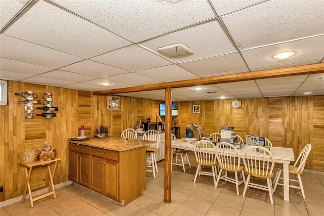 dining space featuring light tile patterned floors, visible vents, and wooden walls