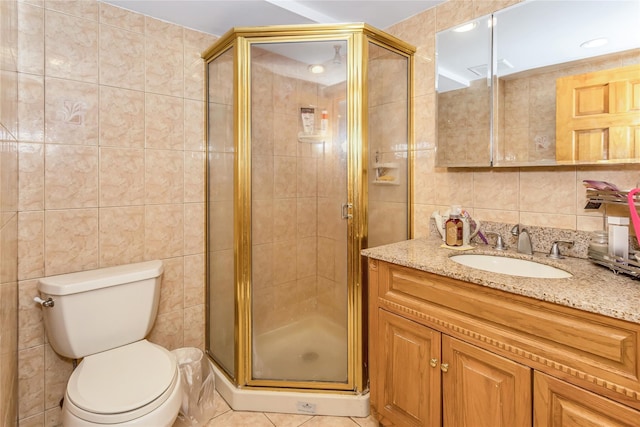 full bathroom with vanity, a shower stall, tile walls, toilet, and tile patterned floors