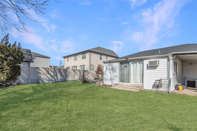 back of property with a wall unit AC, entry steps, a yard, and fence