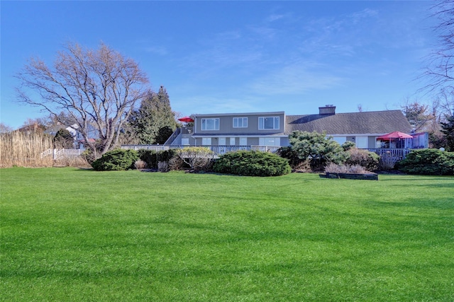view of front of house featuring a chimney, a front yard, and fence