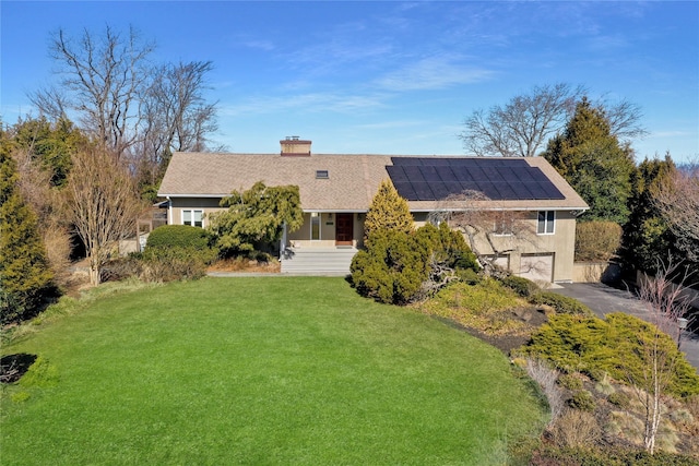 back of property featuring solar panels, an attached garage, a lawn, a chimney, and driveway