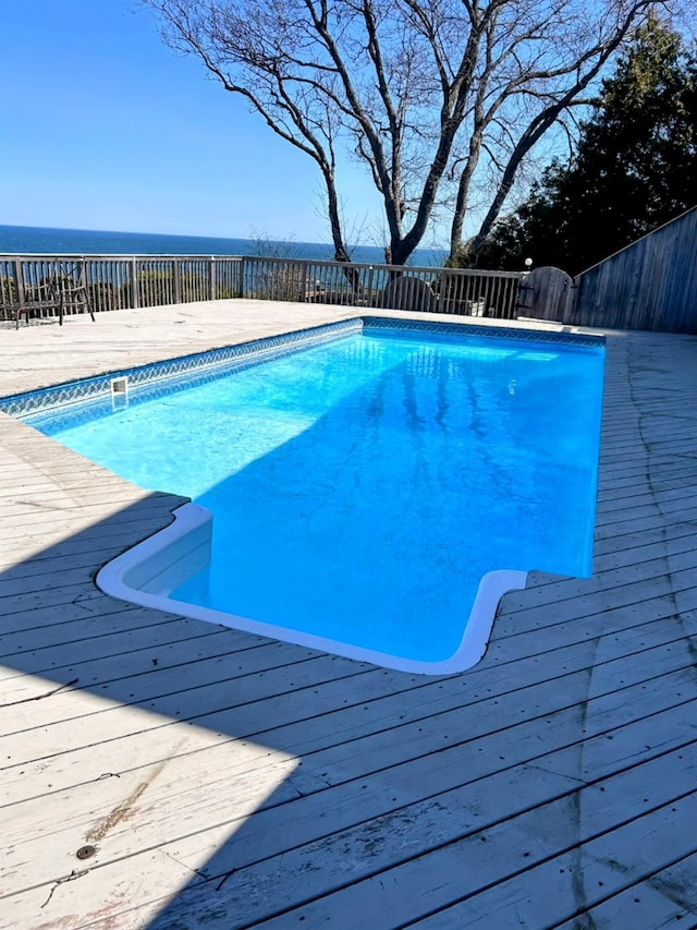 view of pool with a deck with water view and a fenced in pool