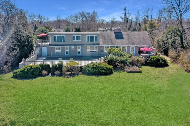 rear view of house with a deck, a yard, and a chimney