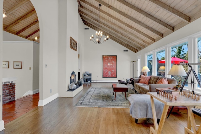 living area featuring beamed ceiling, a warm lit fireplace, wood finished floors, baseboards, and wood ceiling