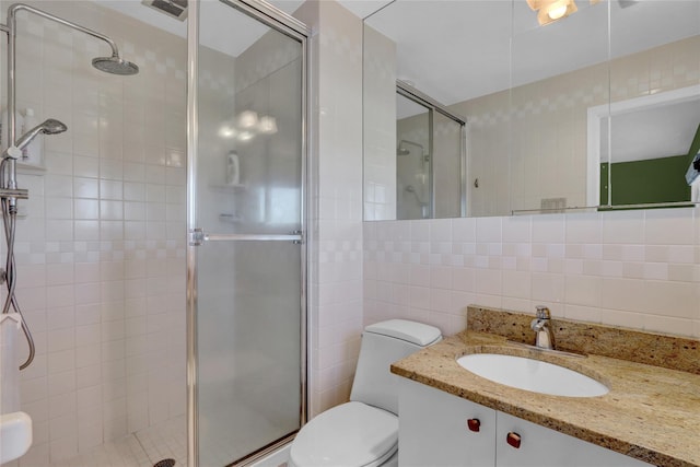 bathroom featuring vanity, a stall shower, tile walls, toilet, and tasteful backsplash
