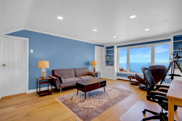 office area featuring built in shelves, a water view, recessed lighting, light wood finished floors, and baseboards