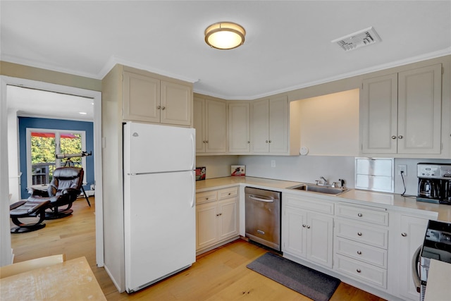 kitchen featuring visible vents, a sink, stainless steel appliances, light wood-style floors, and light countertops