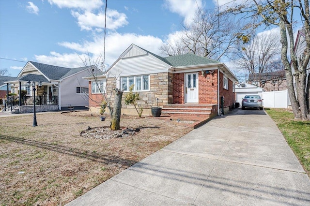 bungalow-style house with fence, roof with shingles, a garage, stone siding, and brick siding