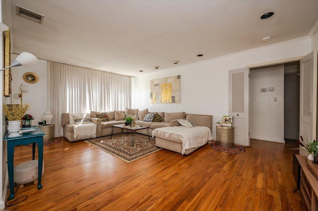 living room with visible vents, wood finished floors, and crown molding