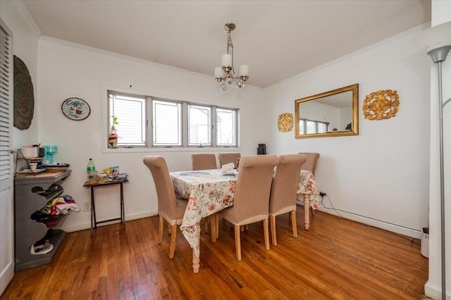 dining space with crown molding, wood finished floors, baseboards, and a chandelier