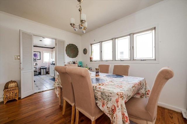 dining area featuring a chandelier, a healthy amount of sunlight, ornamental molding, and wood finished floors