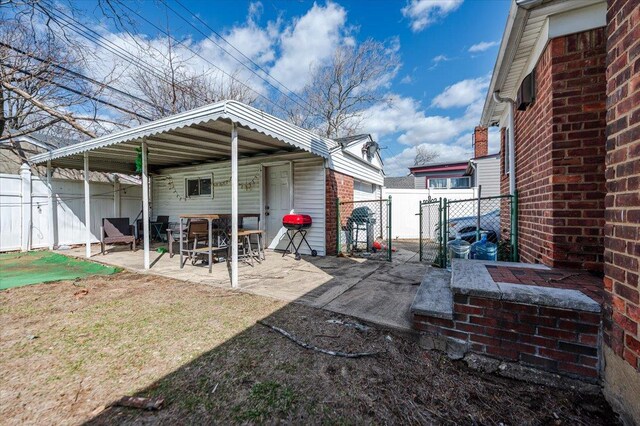 exterior space with a patio area, a gate, brick siding, and fence