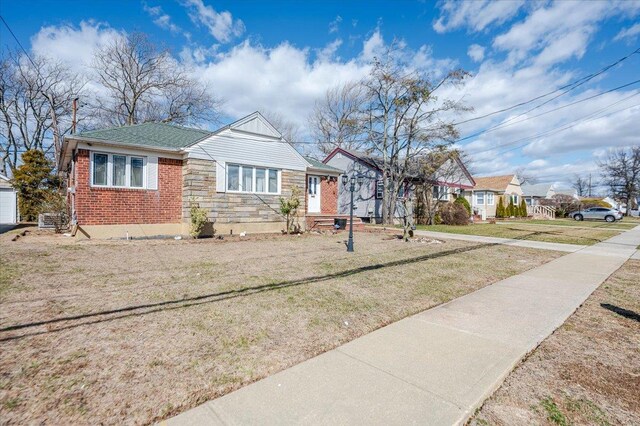 bungalow with brick siding, stone siding, and a front yard