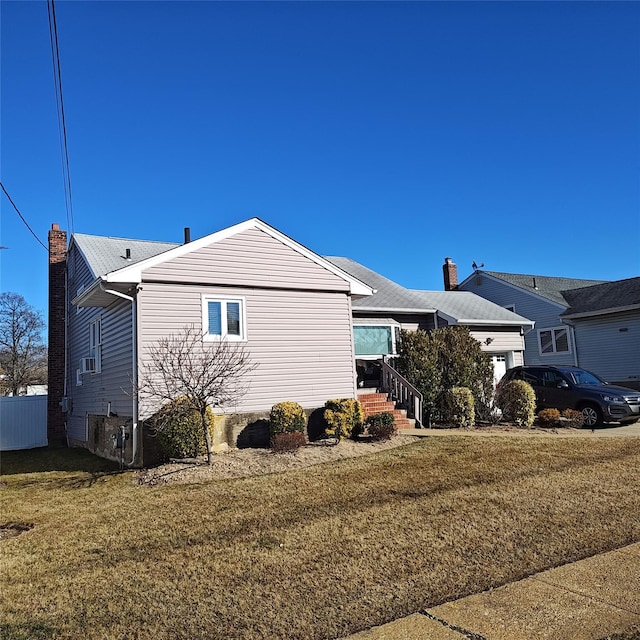 view of side of home with a lawn, an attached garage, a chimney, and fence