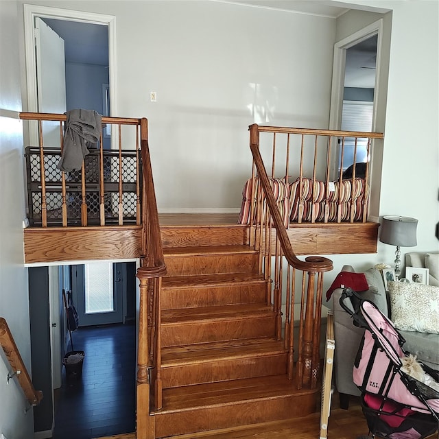 staircase with baseboards and wood finished floors