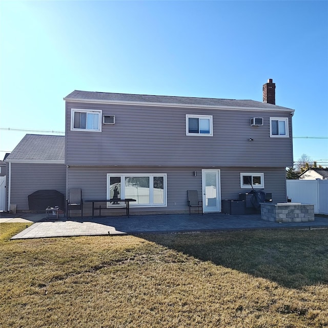 rear view of house with a yard, a patio, a chimney, and fence