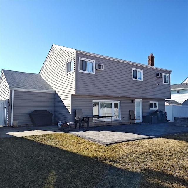 rear view of property featuring a patio, a yard, fence, and a chimney