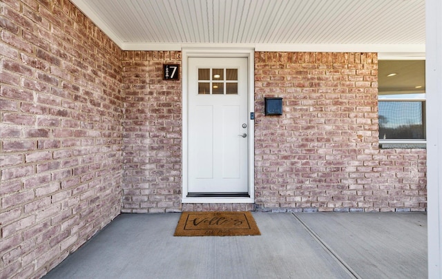 doorway to property with brick siding and a porch